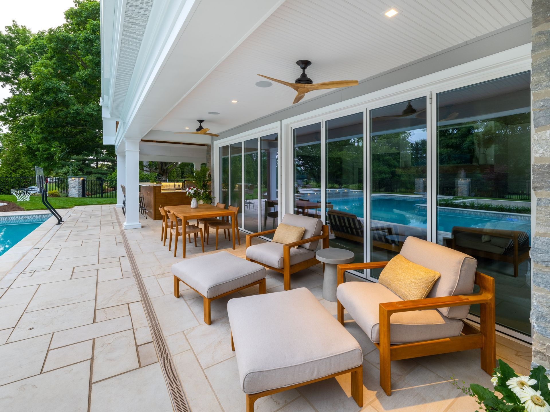 A patio with chairs and ottomans next to a swimming pool