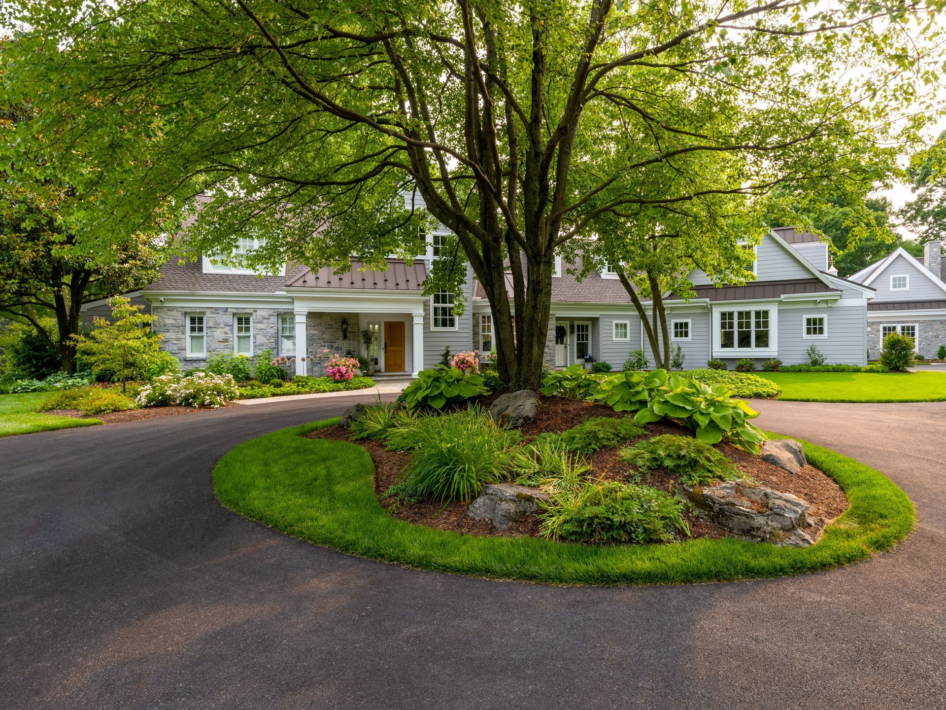 A large house with a tree in the middle of the driveway.
