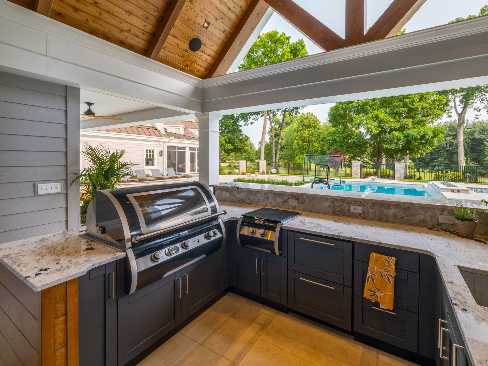 A kitchen with a grill and a swimming pool in the background.