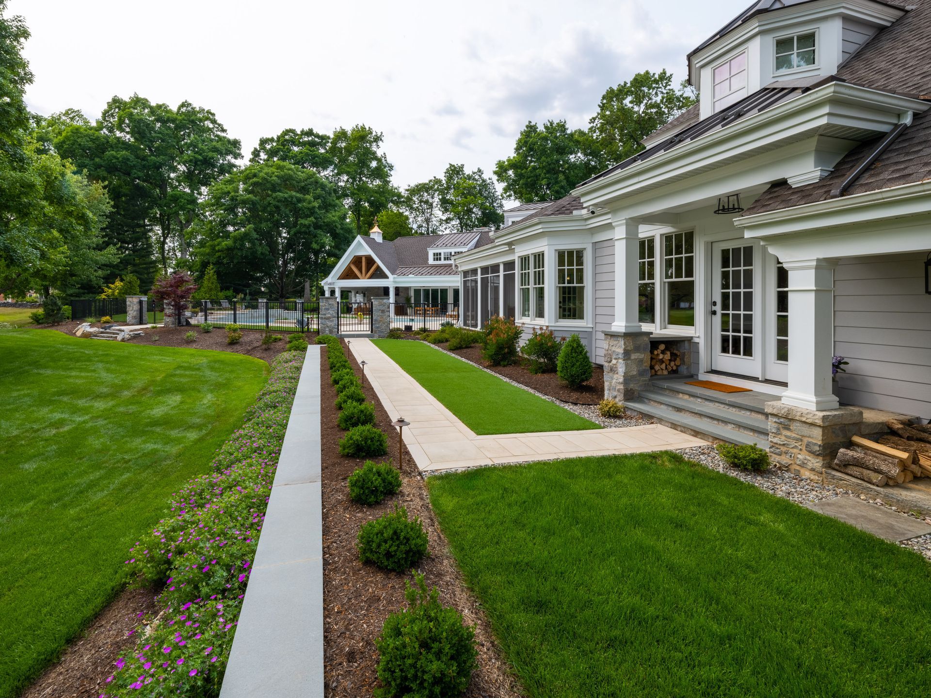 A large white house with a lush green lawn and a walkway leading to it.