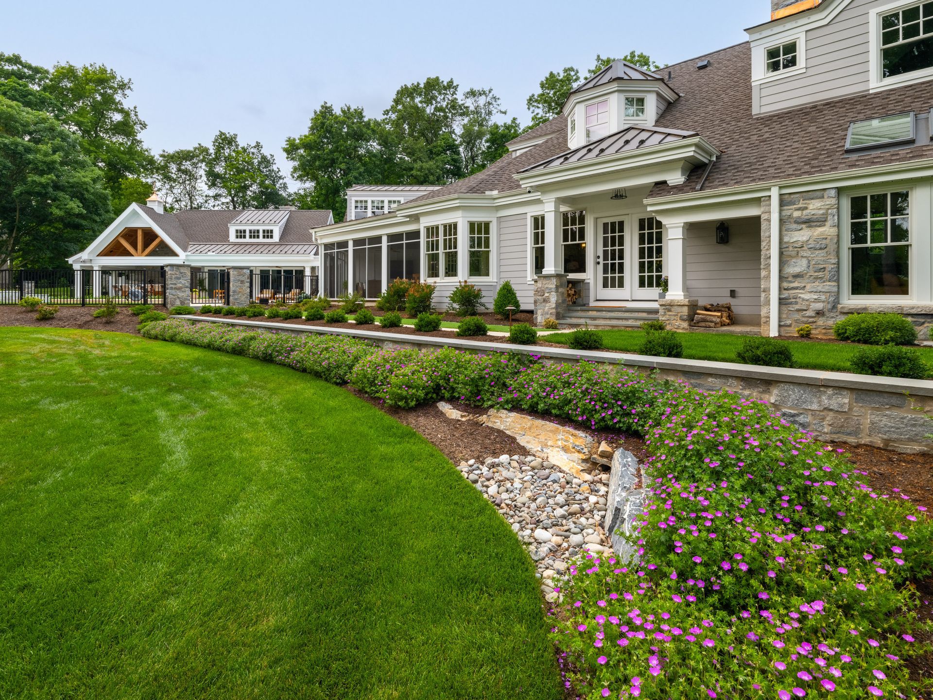 A large house with a lush green lawn and flowers in front of it.