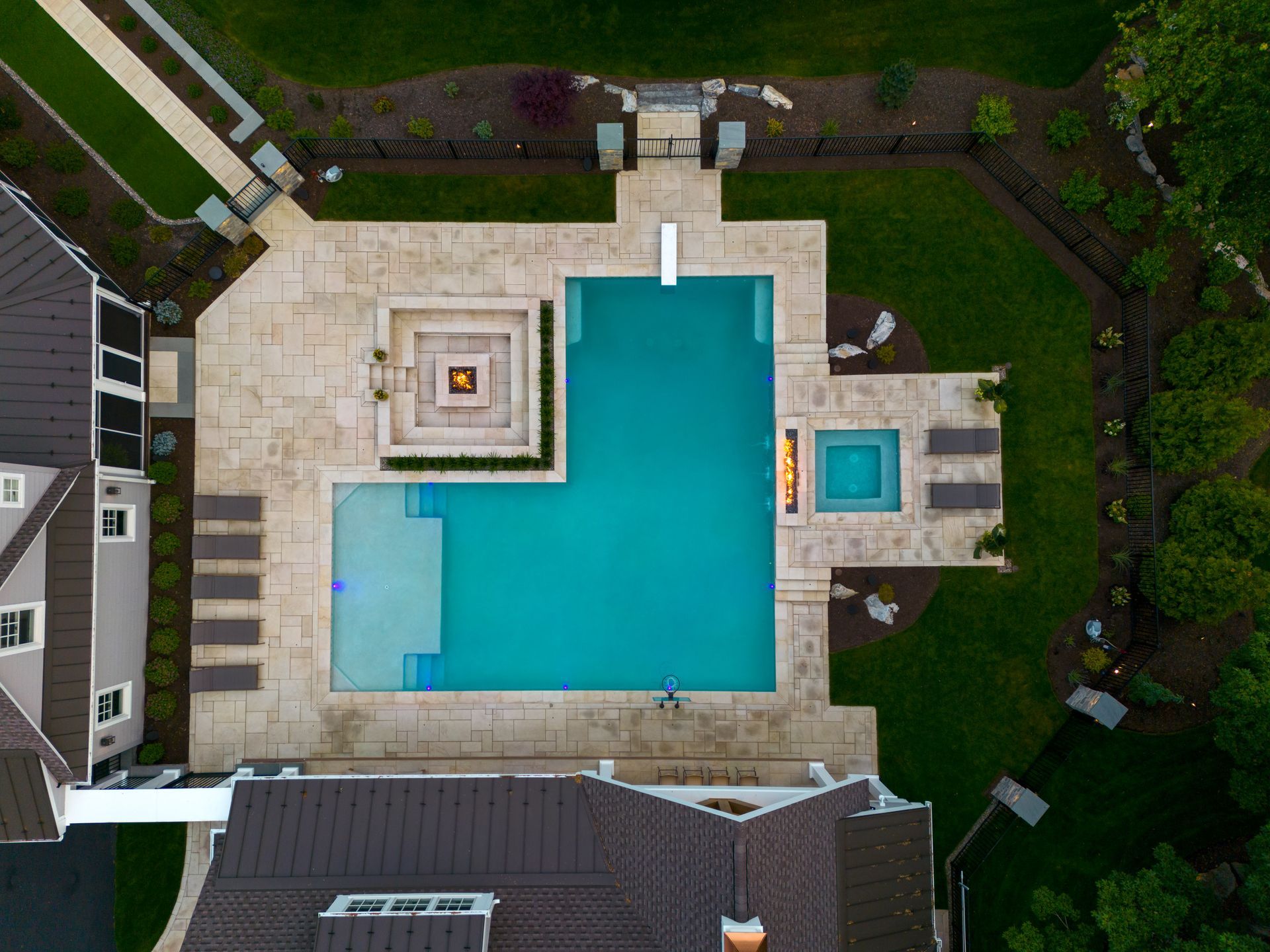 An aerial view of a large swimming pool in the backyard of a house.