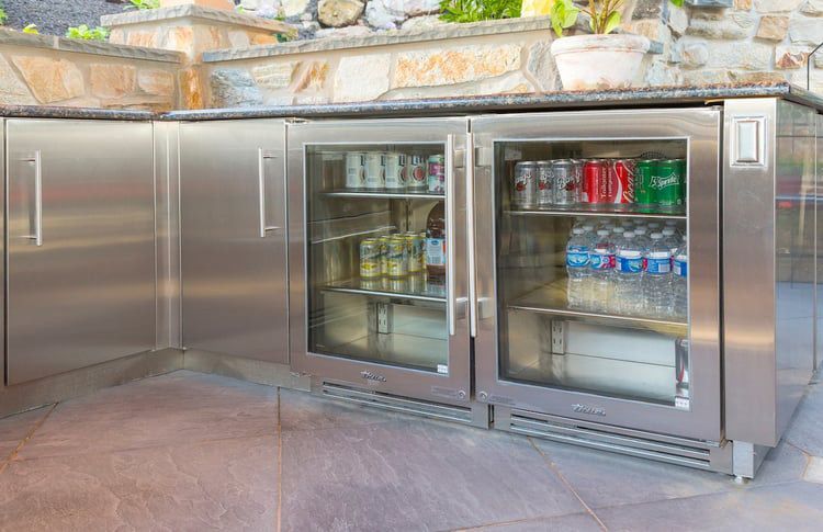 A stainless steel refrigerator with glass doors filled with drinks and cans.