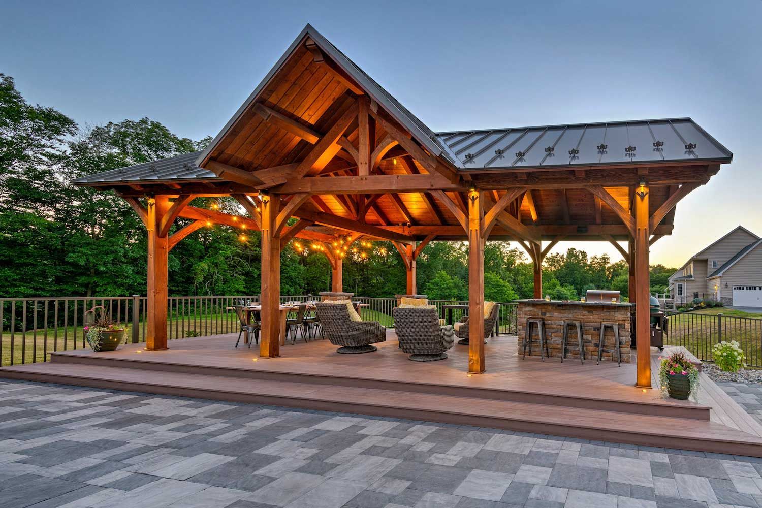 A large wooden pavilion with chairs and tables underneath it.