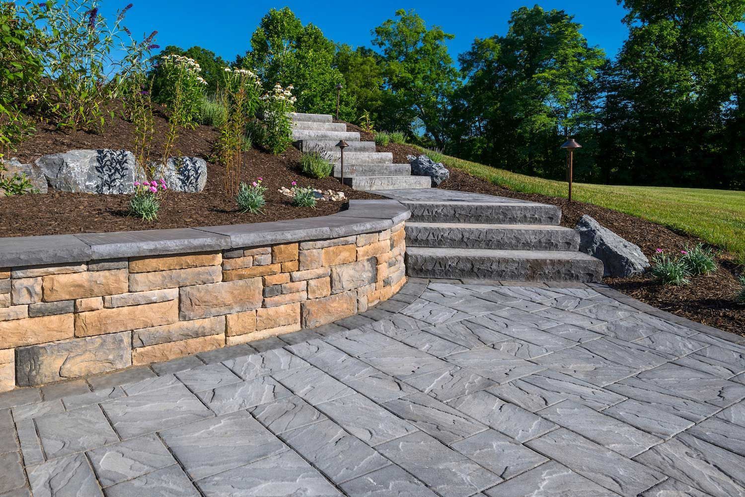 A stone wall with stairs leading up to it in a garden.