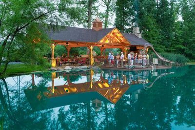 A group of people are standing under a gazebo overlooking a lake.