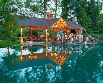 A group of people are standing under a gazebo overlooking a lake.