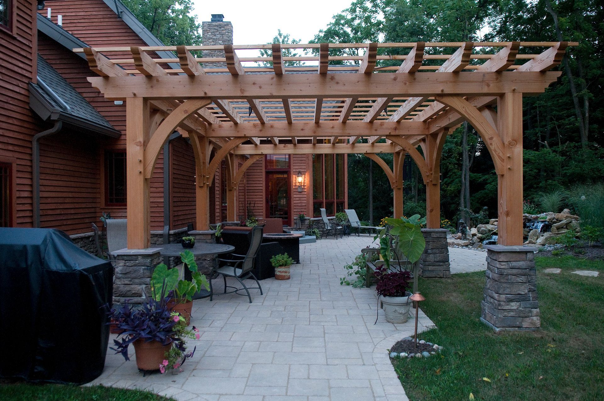 A wooden pergola is in the backyard of a house