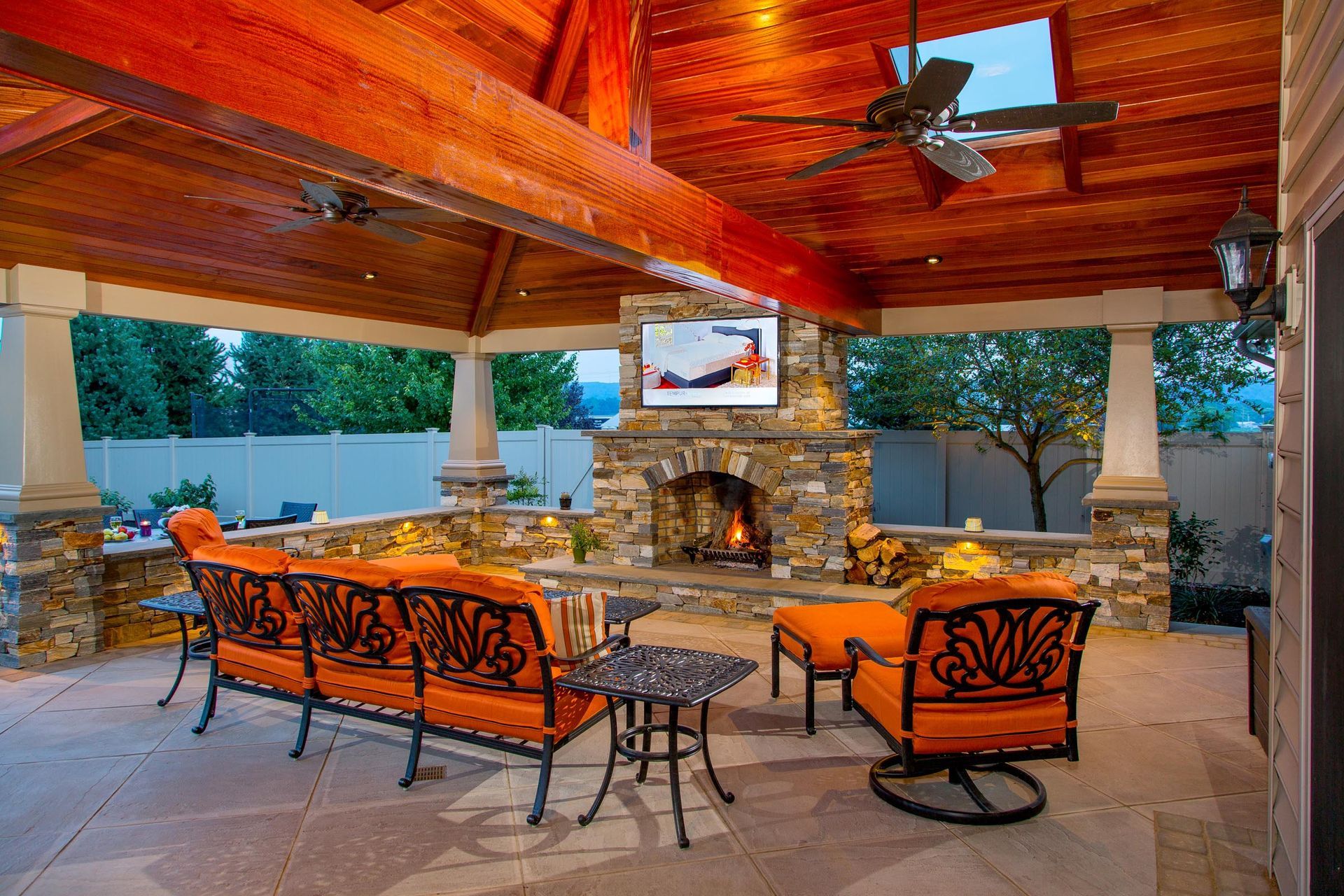A patio with a fireplace , couch , chairs and a television.