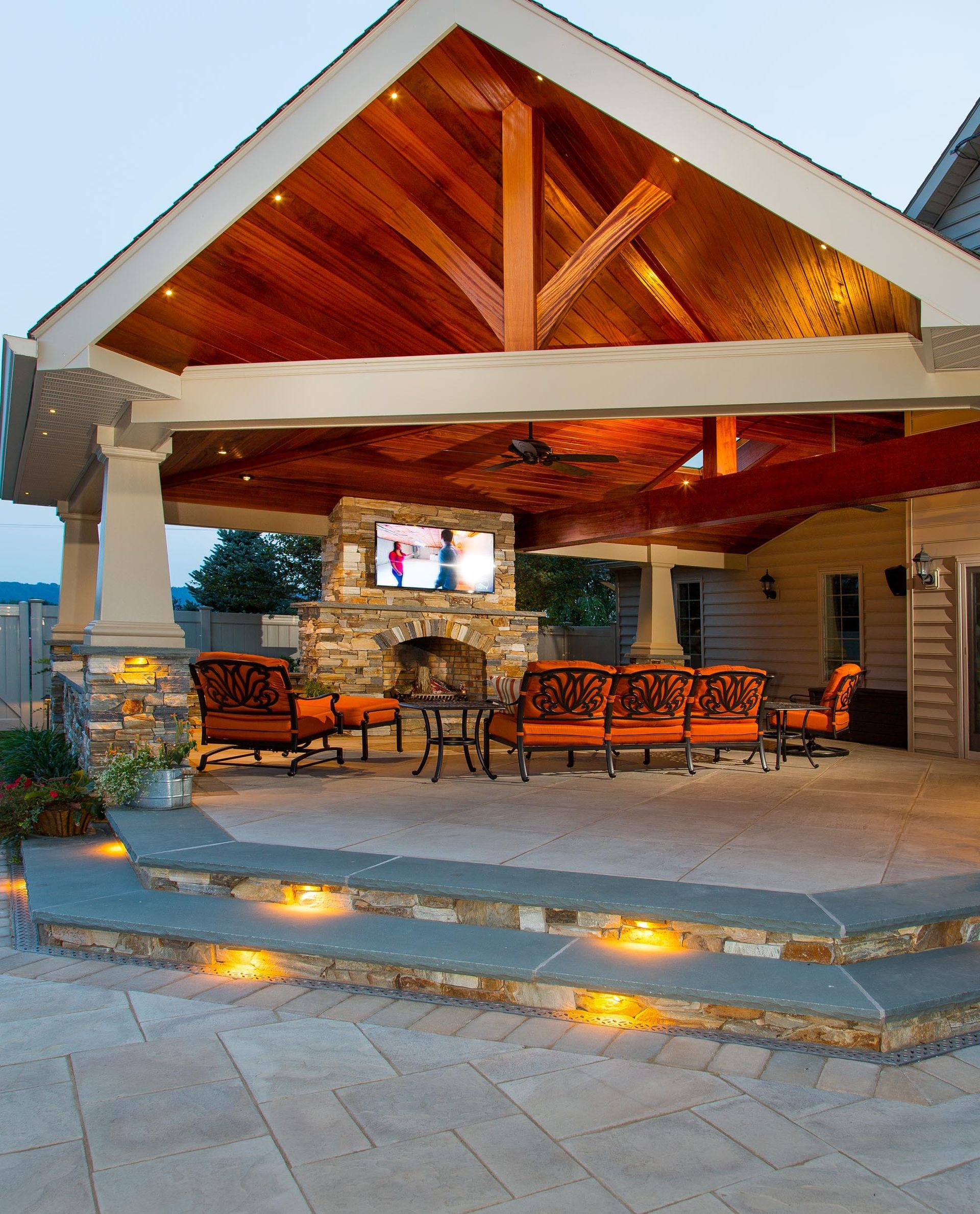 A covered patio with a fireplace and a television