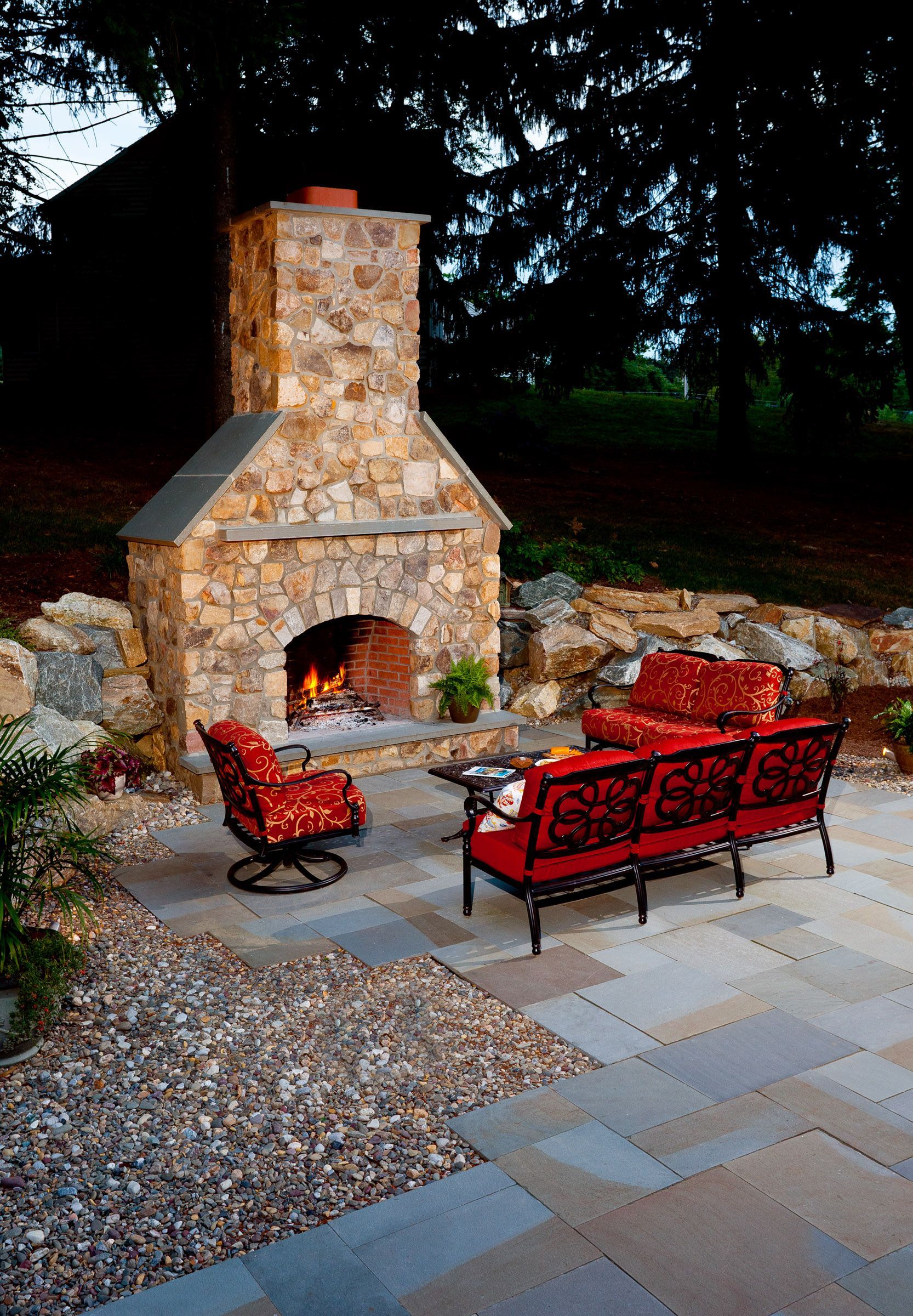 A stone fireplace with a couch and chairs in front of it
