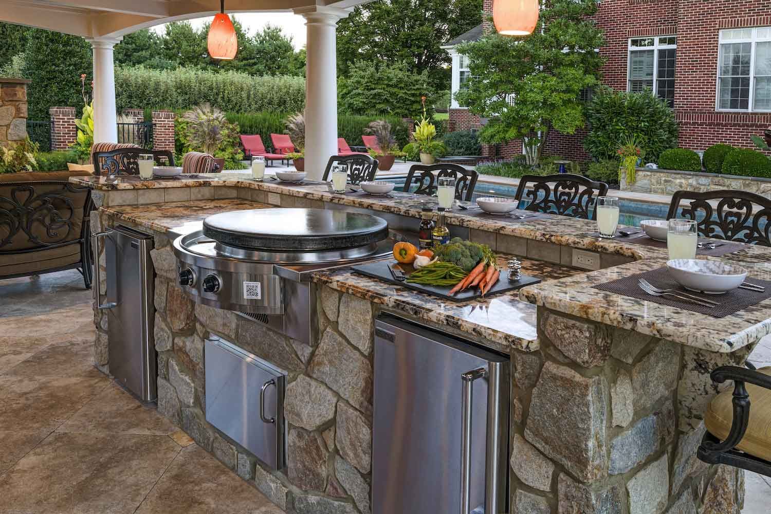 A large outdoor kitchen with granite counter tops and a grill.