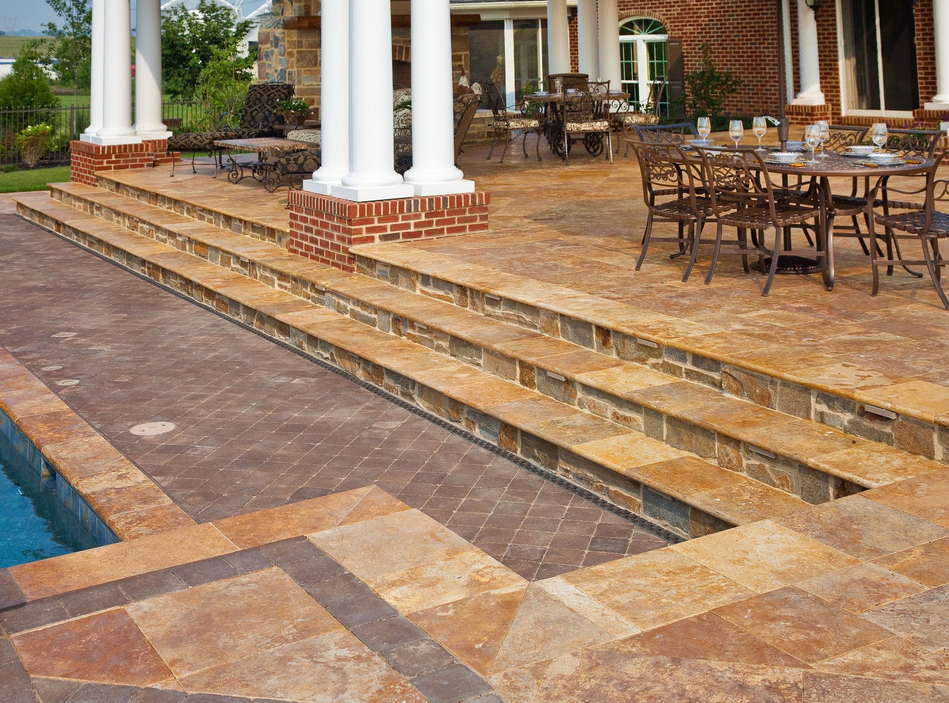 A patio with tables and chairs next to a swimming pool