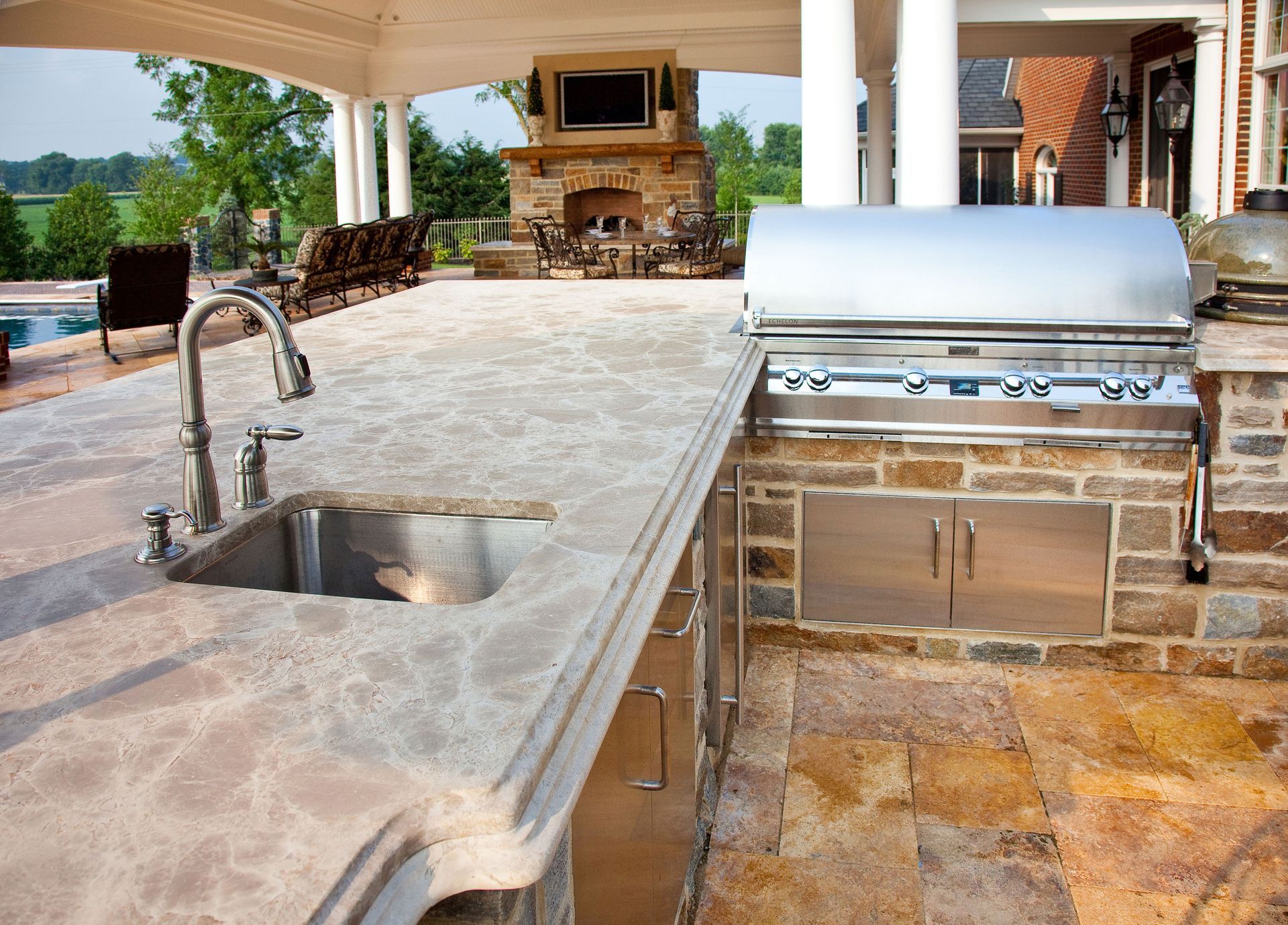 An outdoor kitchen with a stainless steel grill and a sink