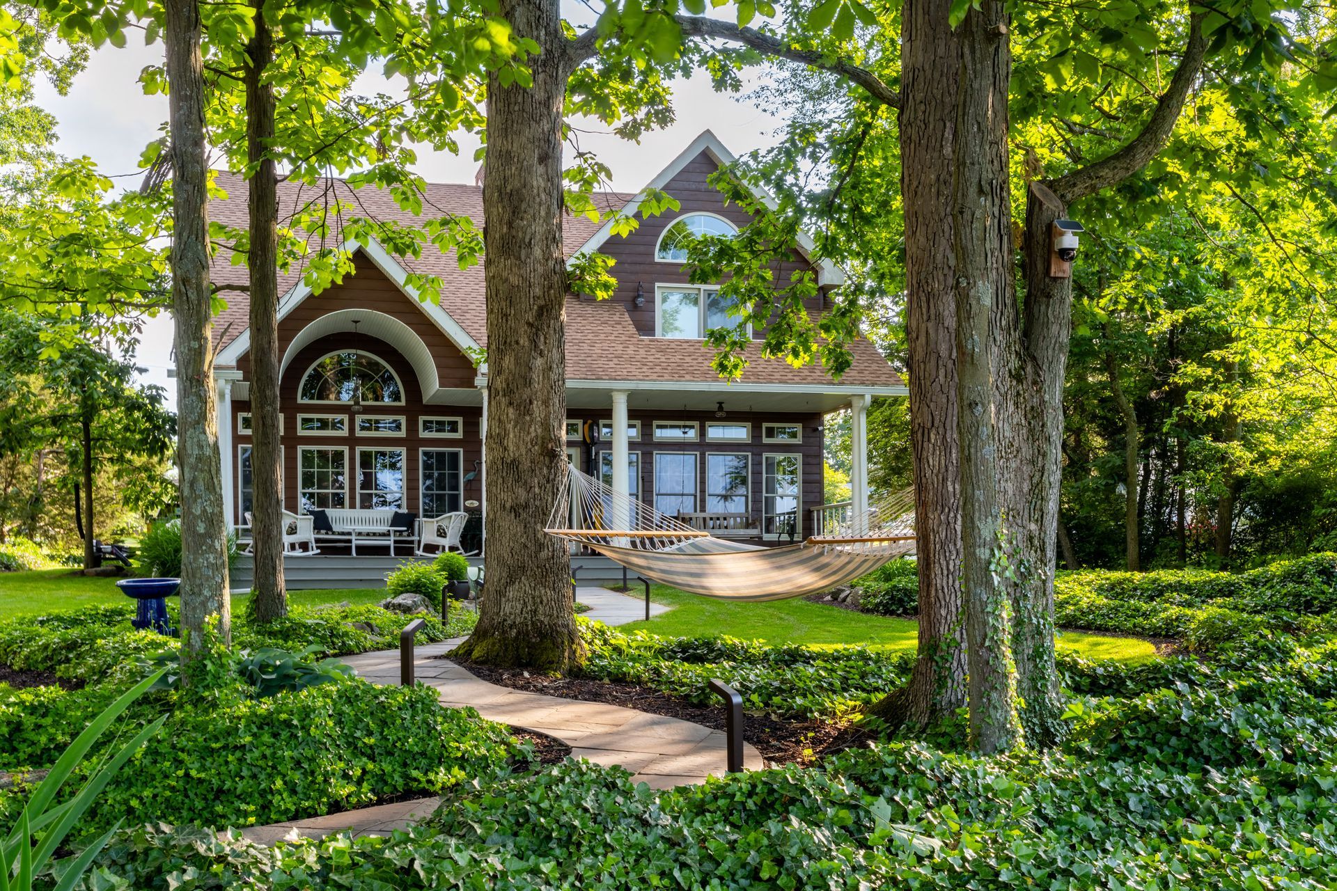 A large house with a walkway leading to it is surrounded by trees.