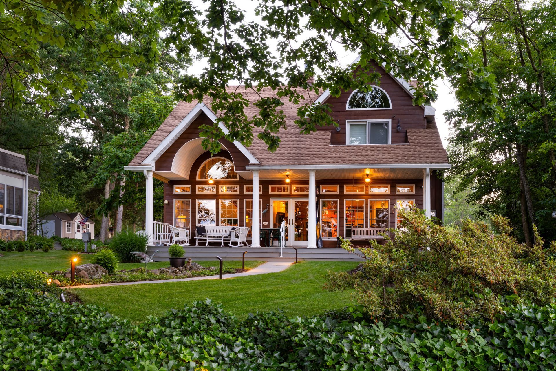 A large house with a large porch is surrounded by trees.