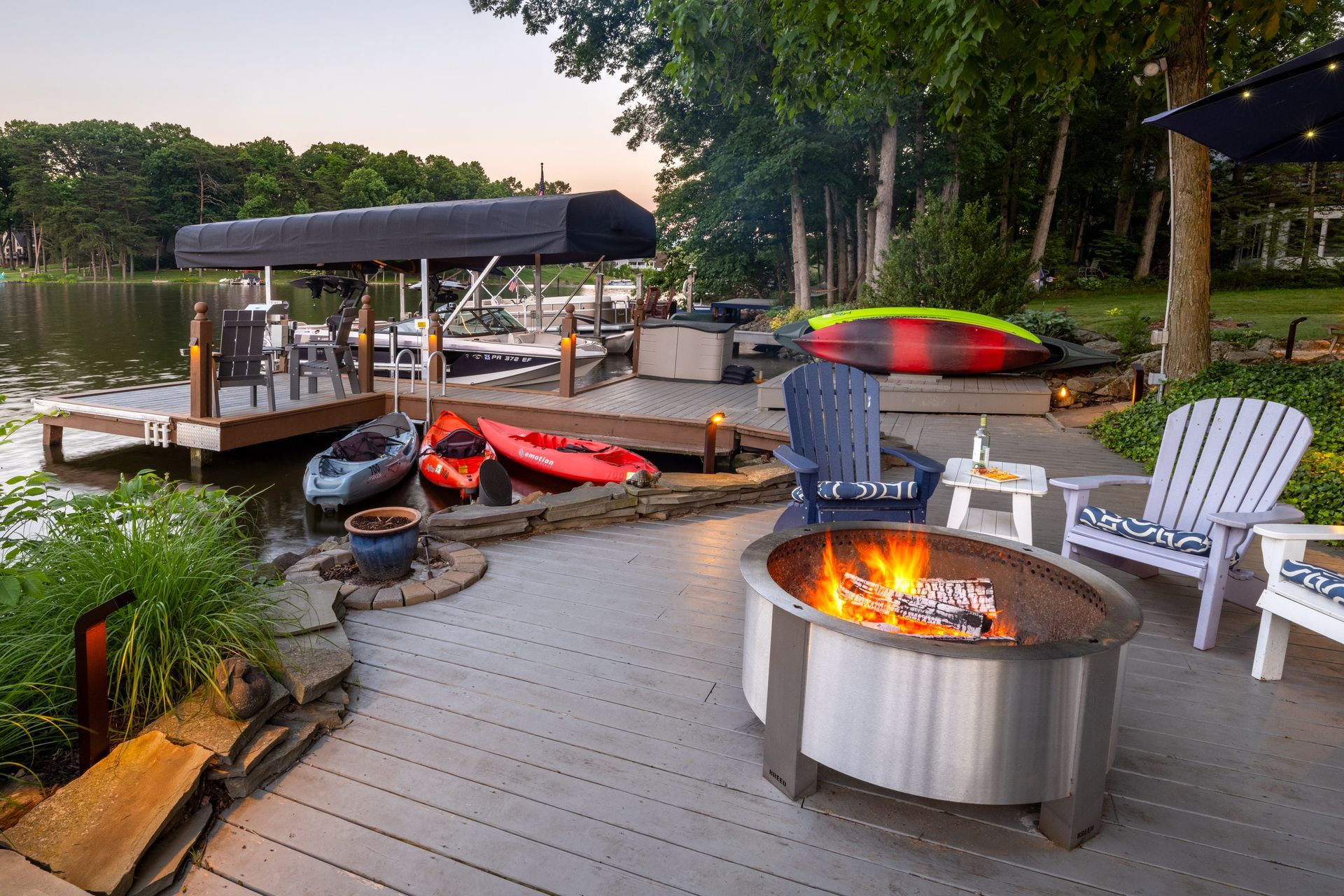 A fire pit is sitting on a deck next to a lake.