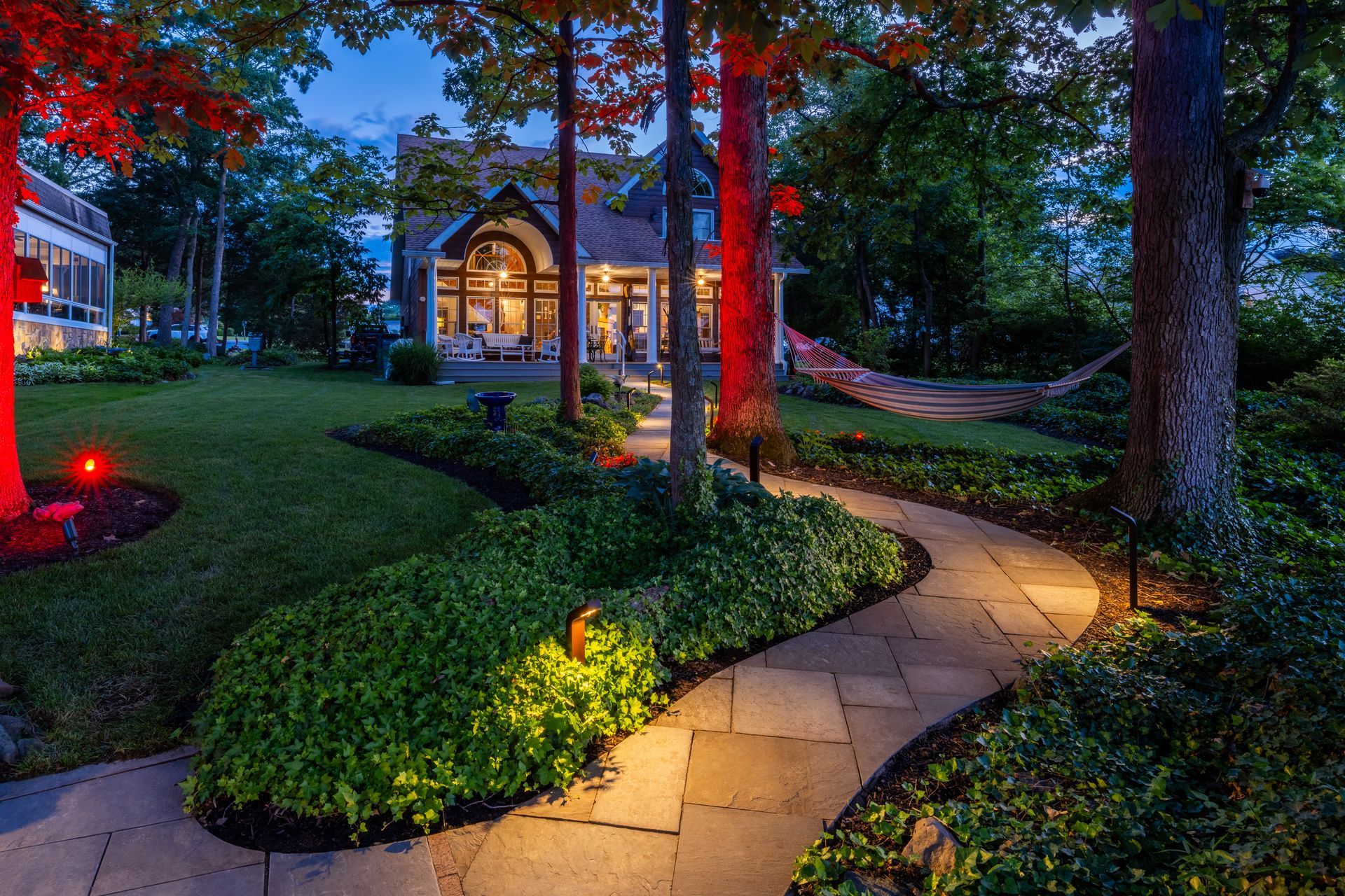 A path leading to a house with a hammock in the backyard at night.