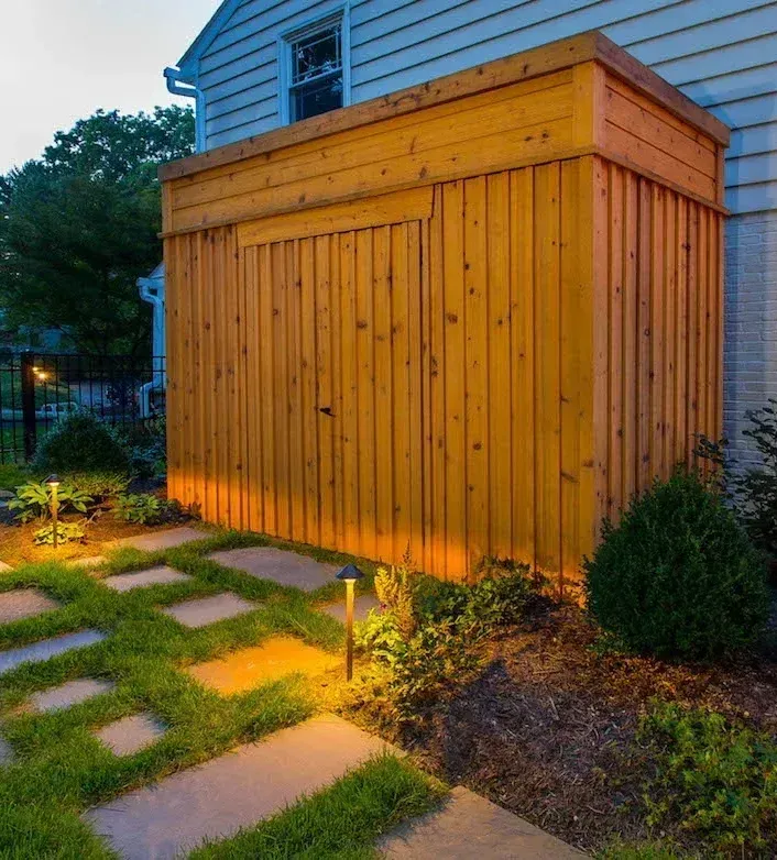A brick wall with a lamp on top of it next to a garage door.