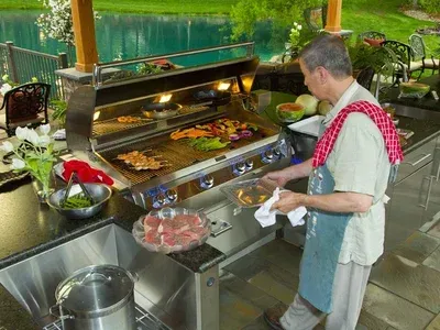 A man is cooking food on a grill in an outdoor kitchen.