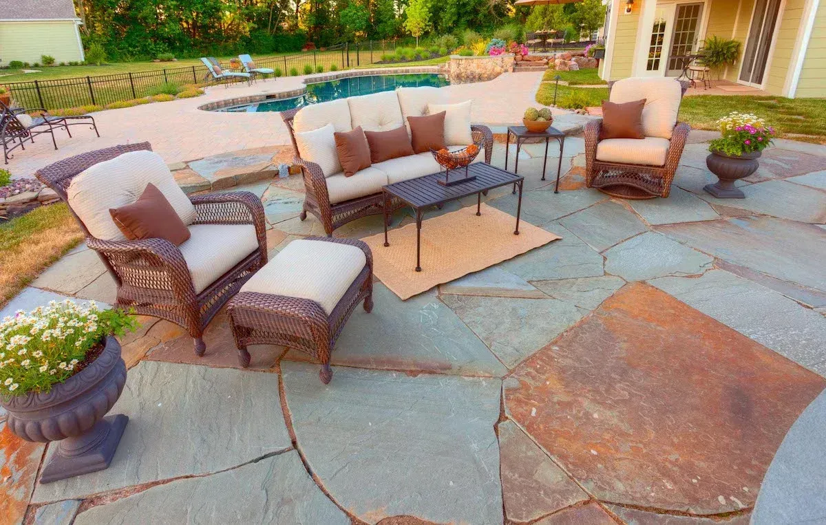 A patio with furniture and a pool in the background.