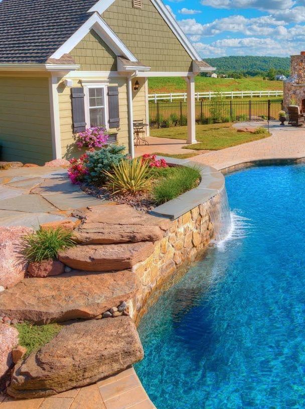 There is a large swimming pool in the backyard of a house.