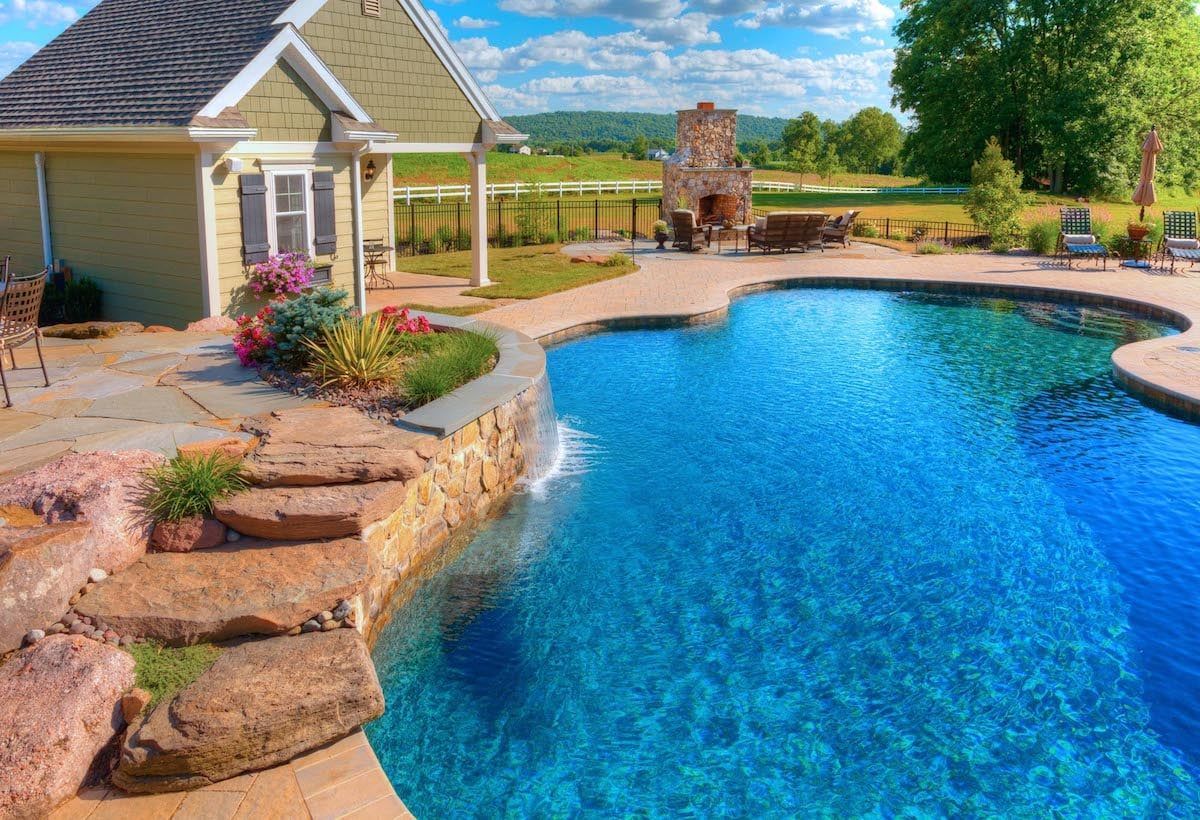 There is a large swimming pool in the backyard of a house.