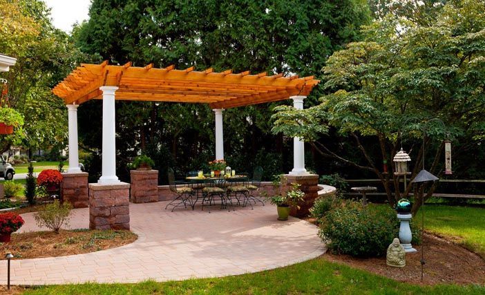 There is a pergola with a table and chairs underneath it in the backyard.