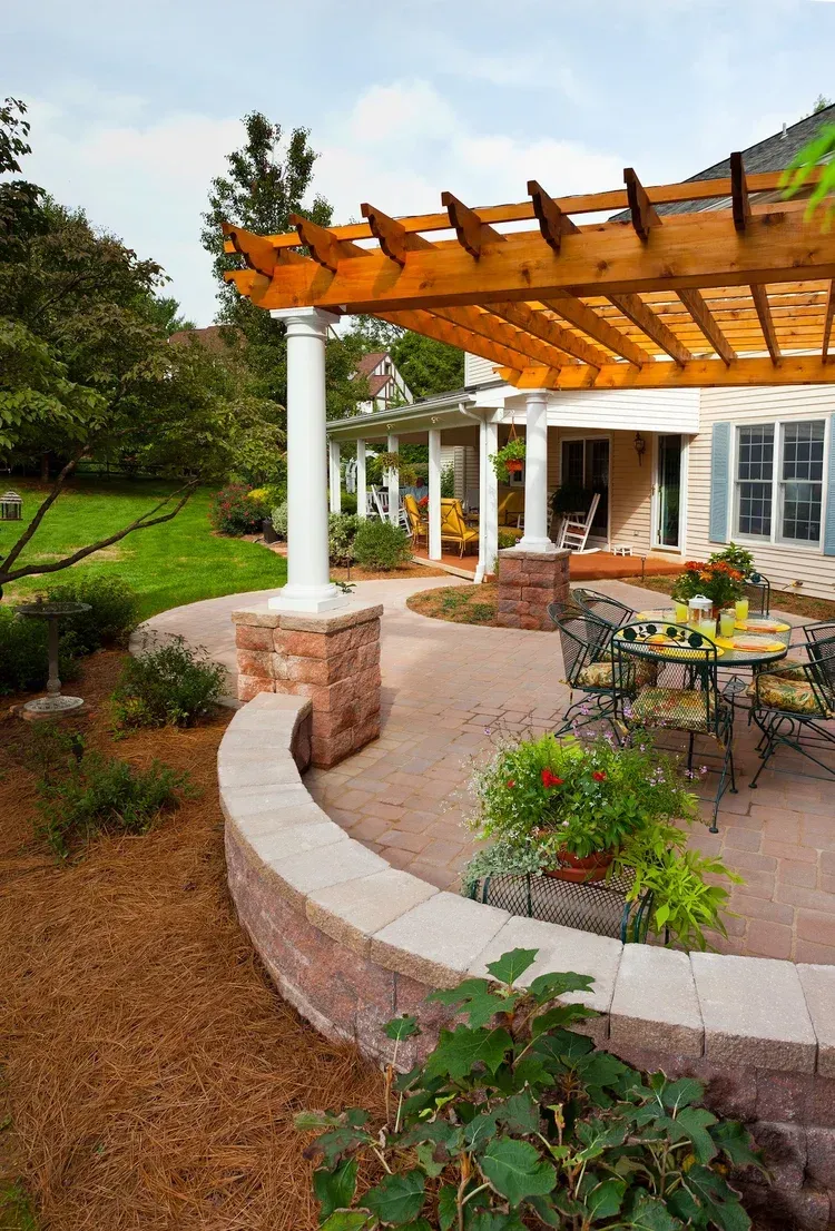 A wooden pergola over a patio with a table and chairs.