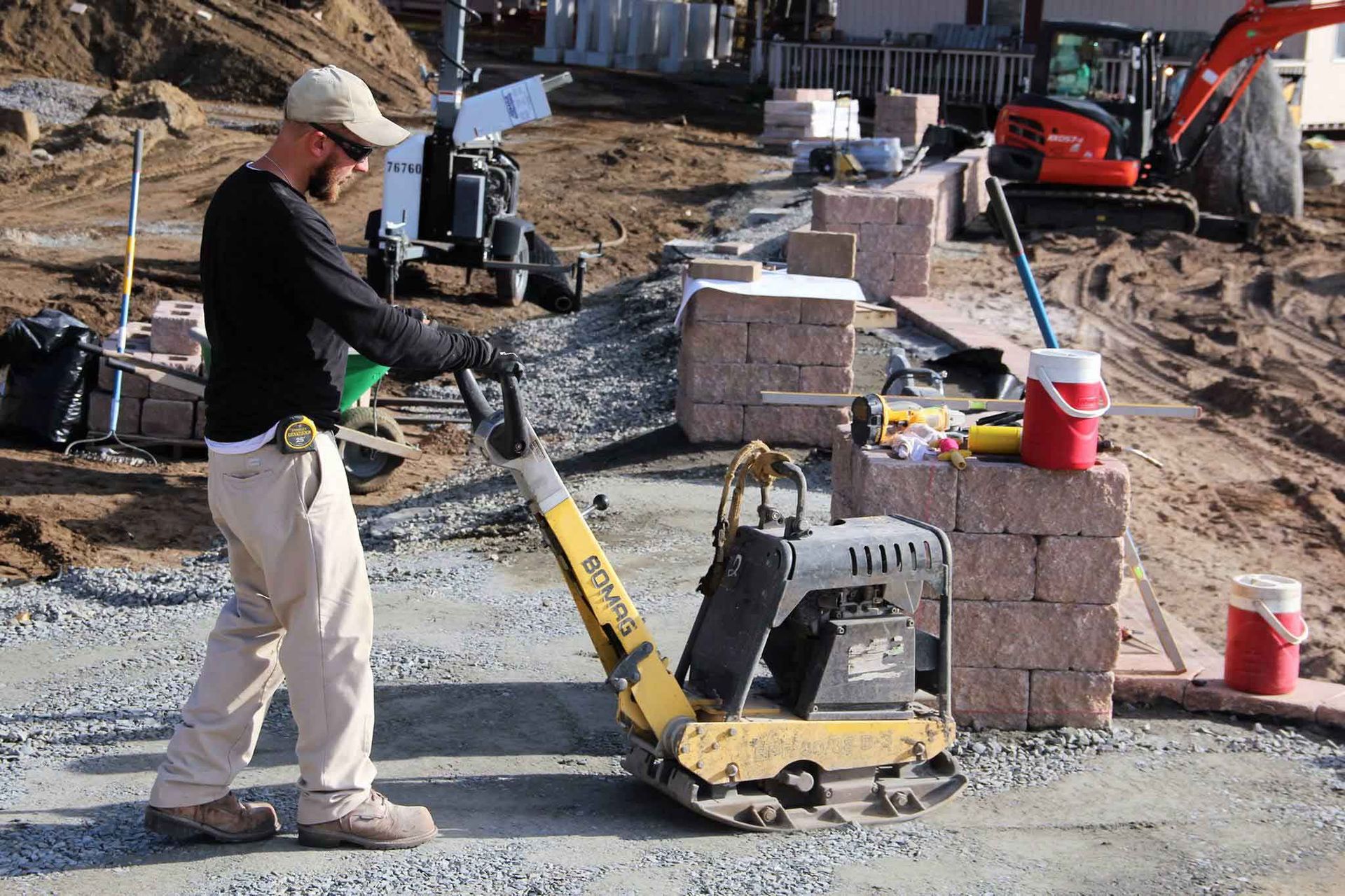 A construction worker is using a vibratory plate compactor on a construction site.