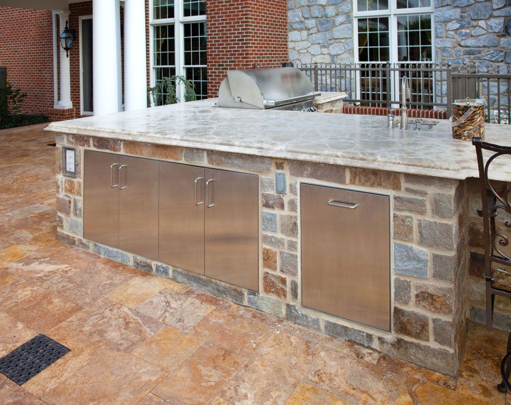 A large outdoor kitchen with stainless steel cabinets and a grill.