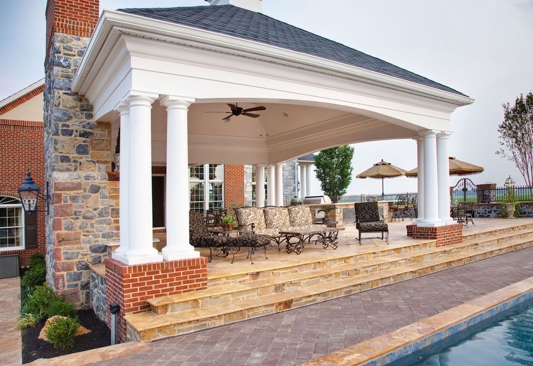 A large covered patio area with a swimming pool in the background.