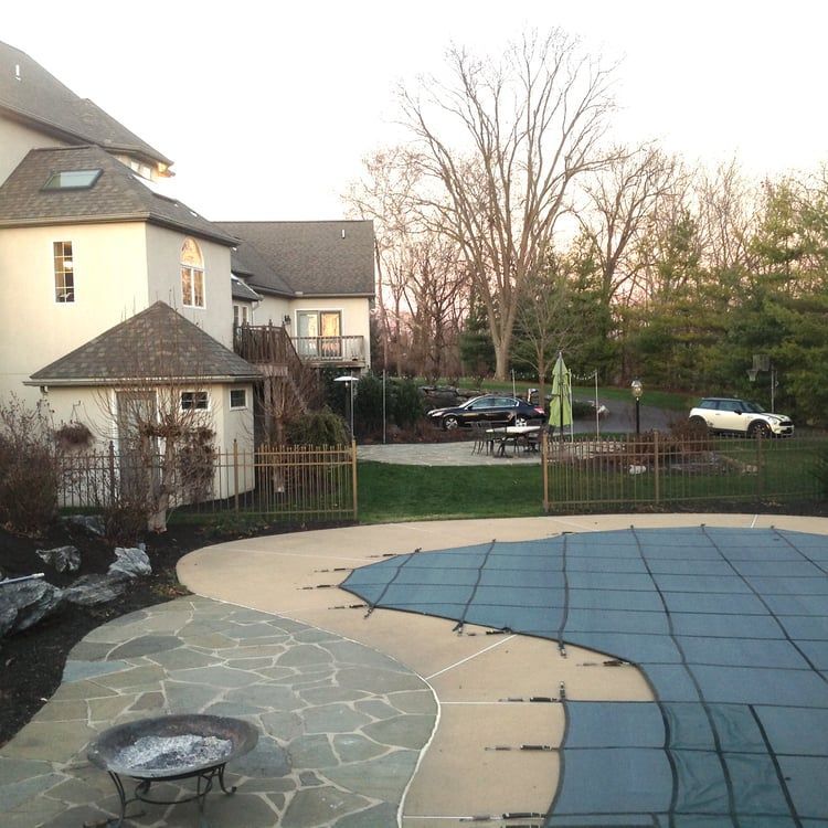 A swimming pool with a blue cover and a fire pit