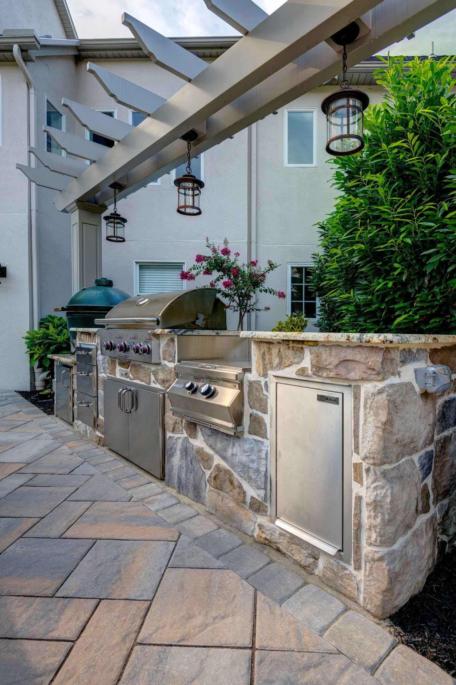 A patio with a grill and a pergola over it.