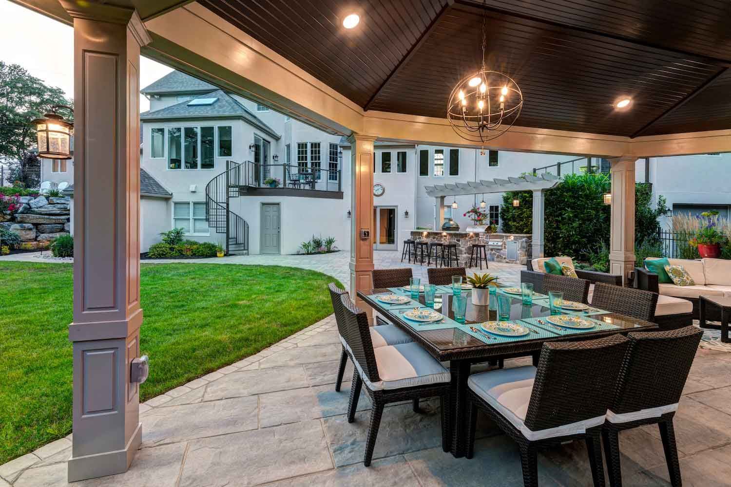 A patio with a table and chairs on it in front of a house.