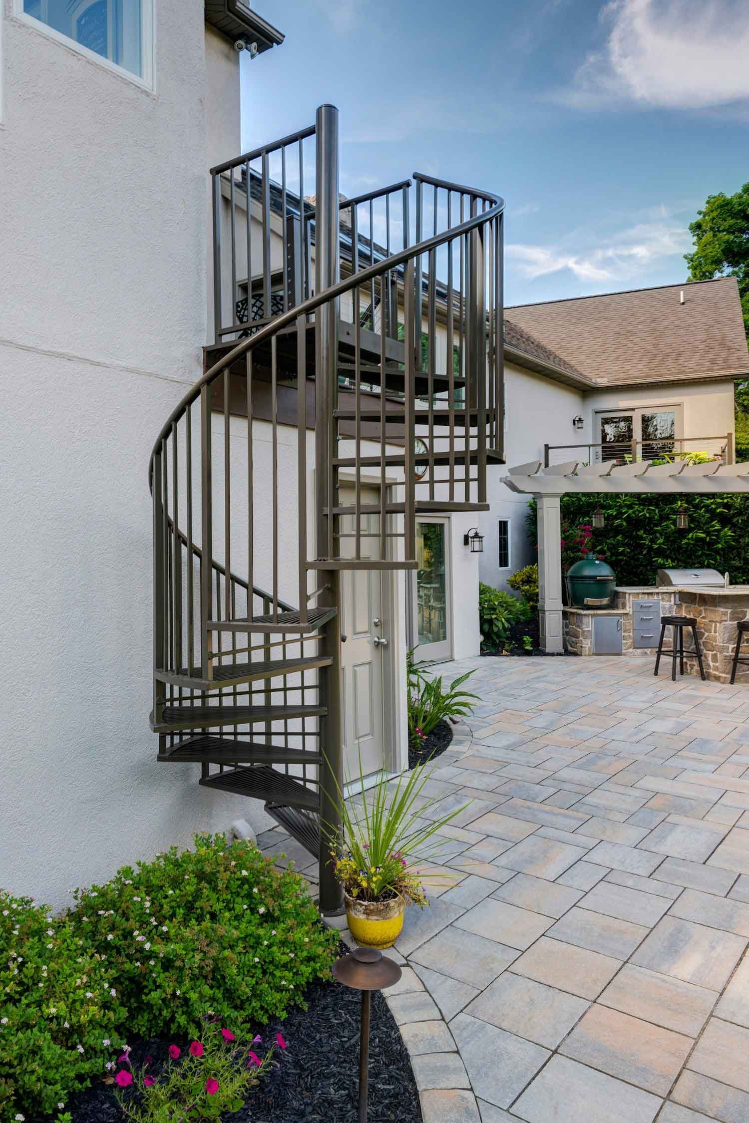 A patio with a table and chairs on it in front of a house.