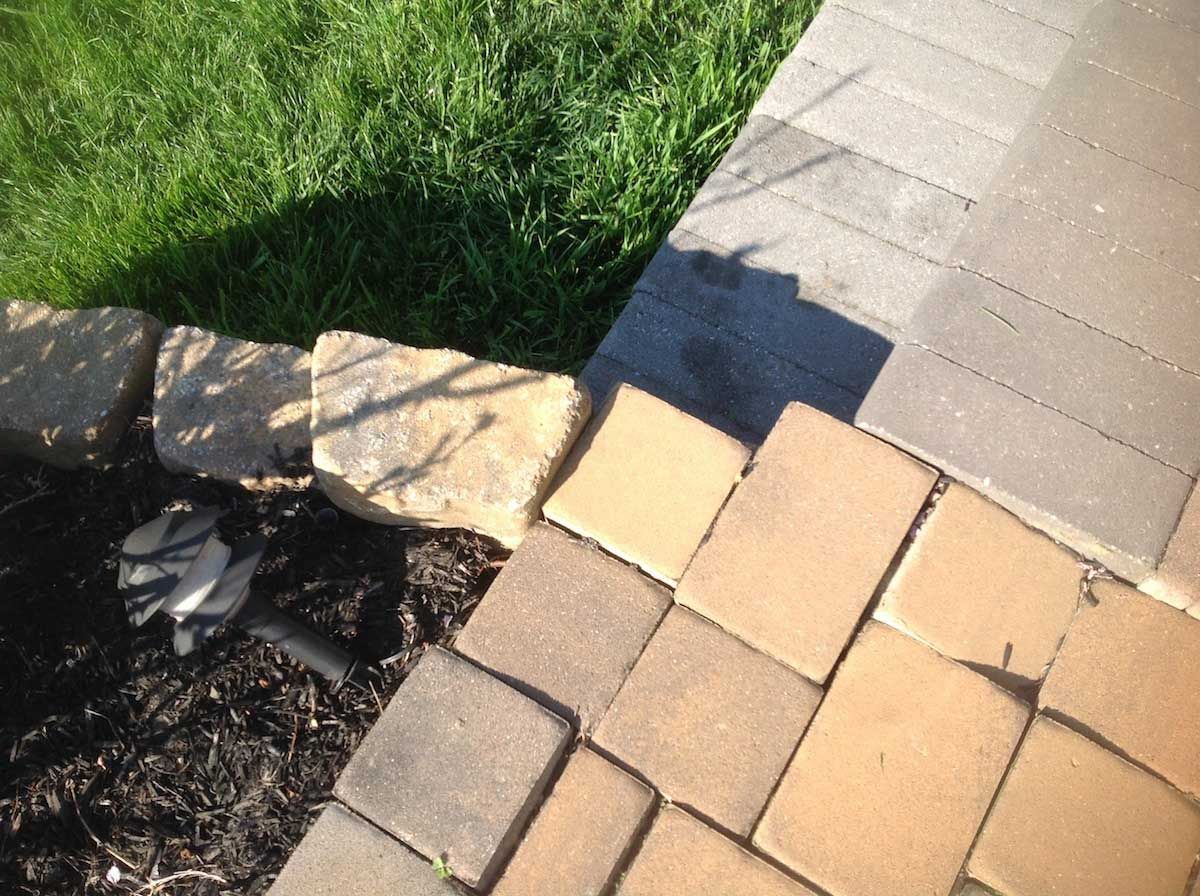 A shadow of a person is cast on a brick sidewalk