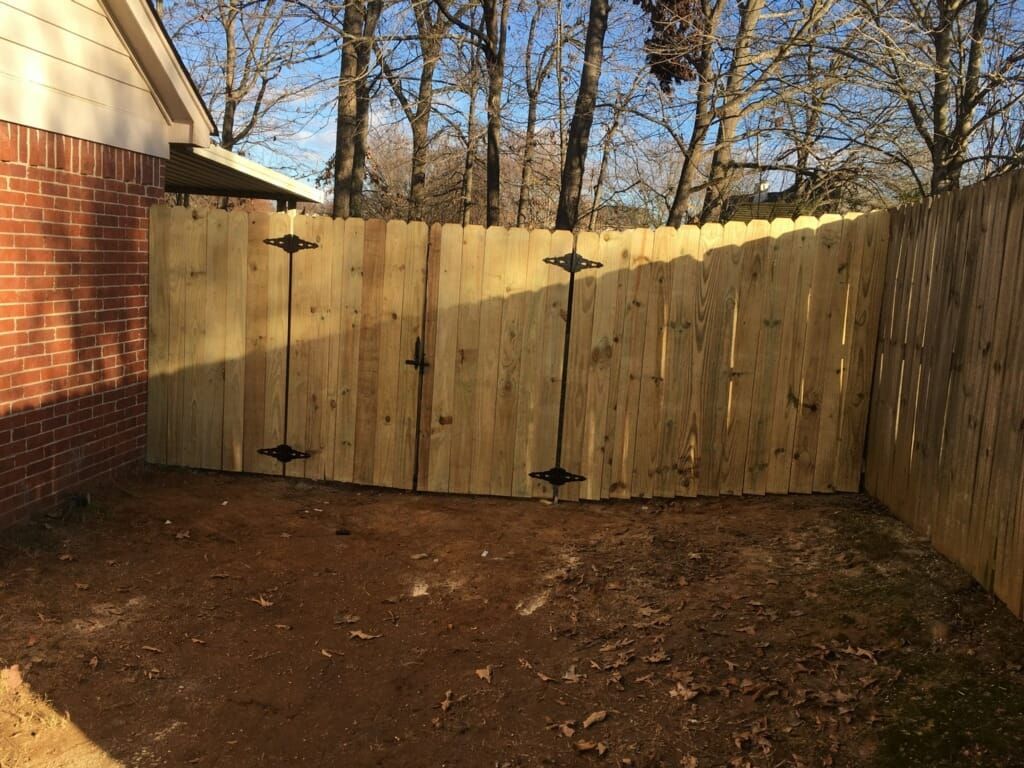Wooden fence with two gate doors in a backyard.
