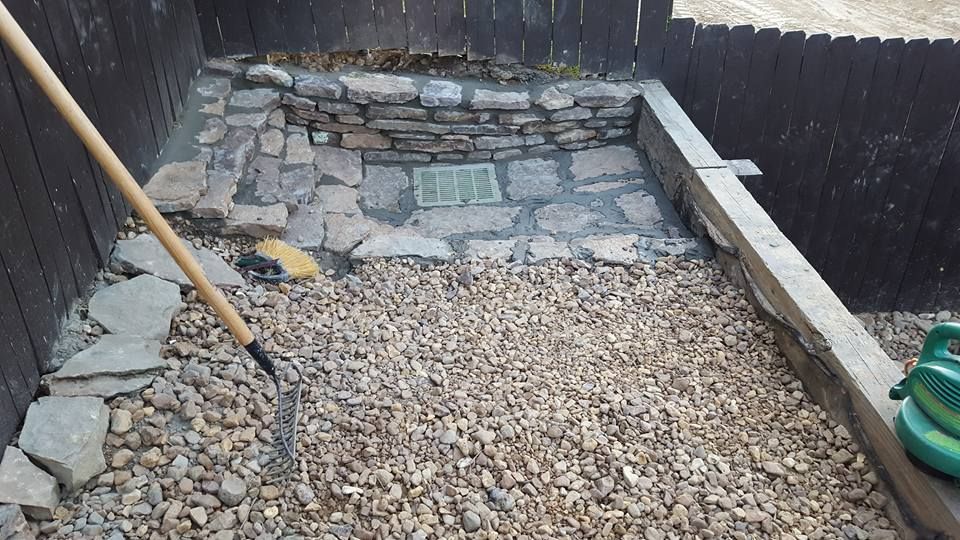 A garden bed being prepped with rocks and stones. A rake and hose are present.