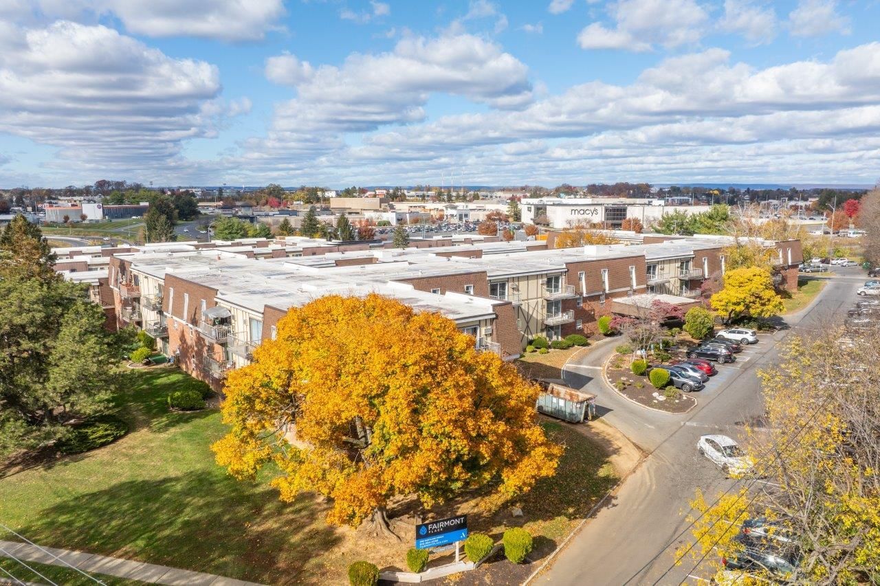 Aerial view of a brick apartment complex with parking lots and fall foliage.