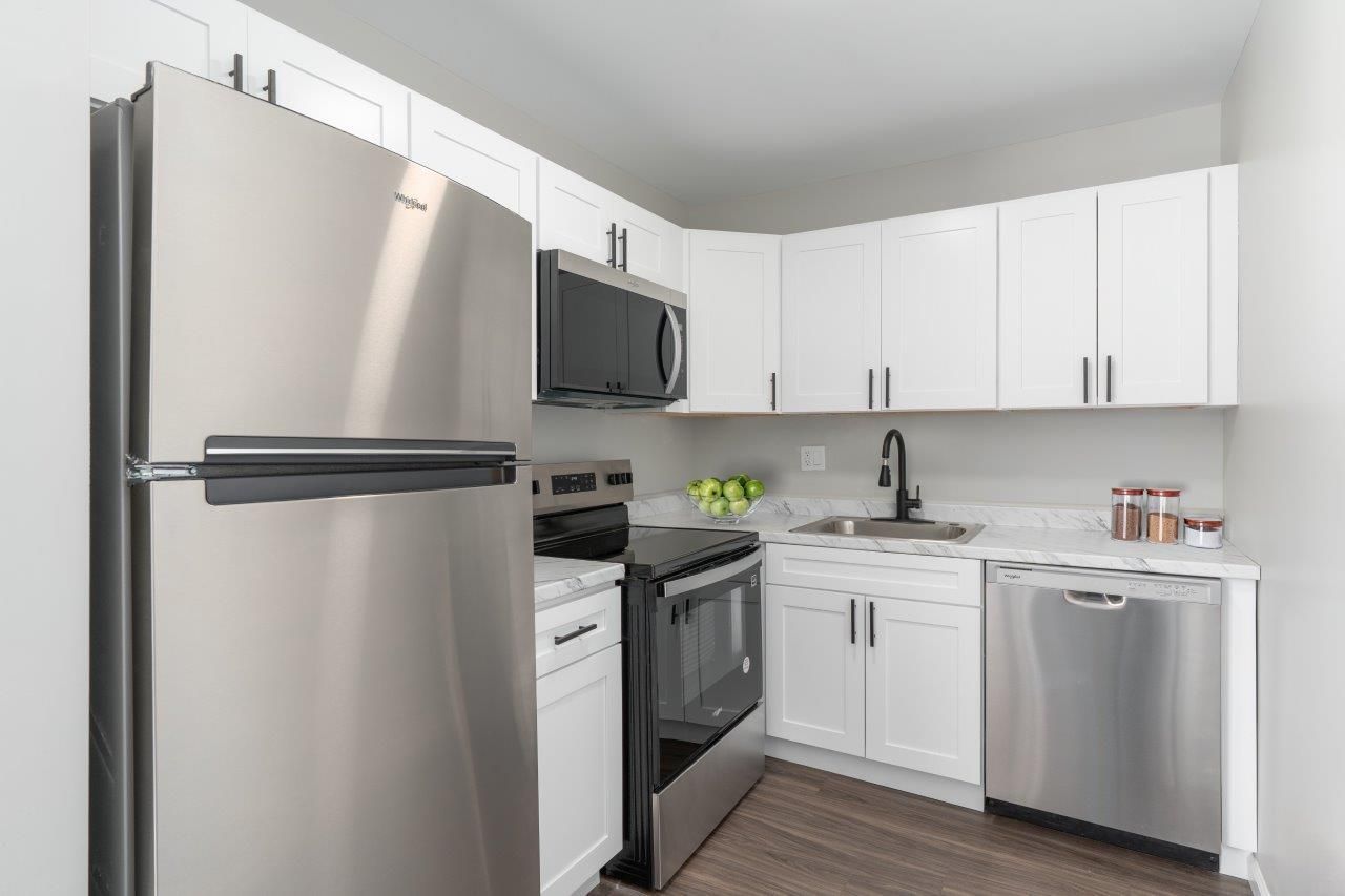 Modern kitchen with white cabinets and stainless-steel fridge, stove, microwave, and dishwasher.