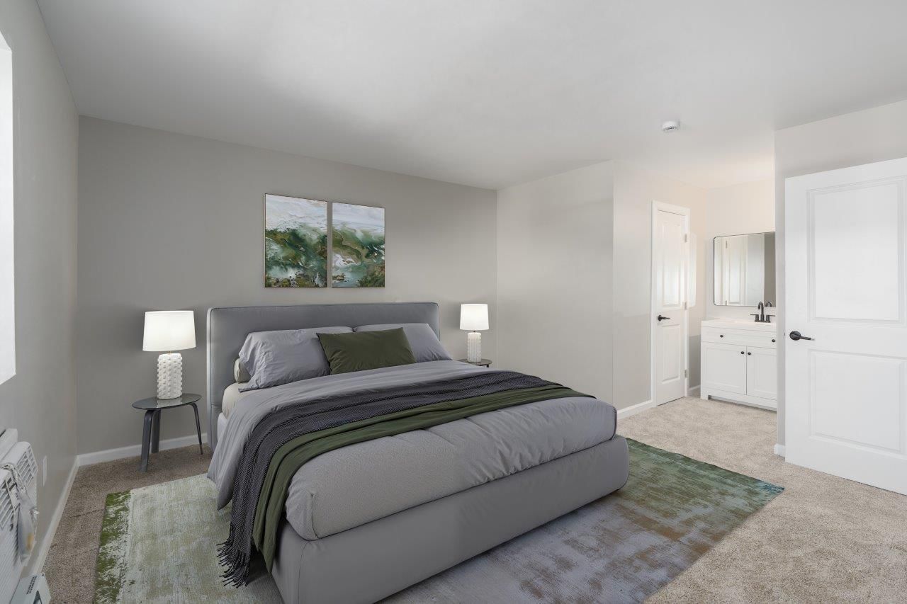 Modern apartment bedroom with a gray upholstered bed and two nightstands.