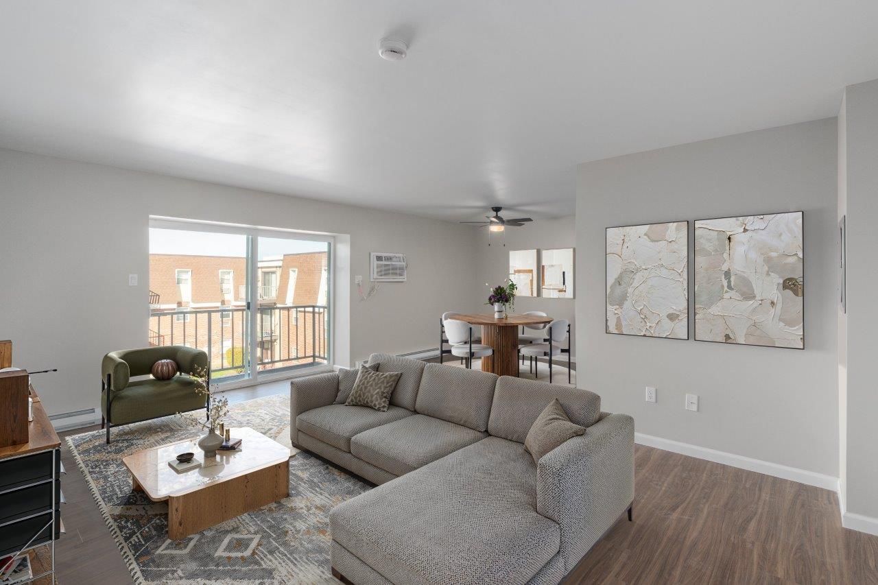 Bright living room with gray sectional sofa, coffee table, and sliding door to balcony.