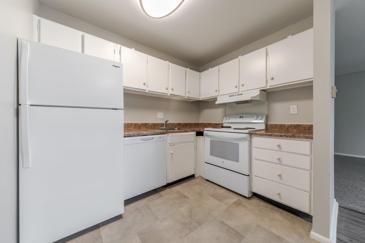 White kitchen with refrigerator, stove, cabinets, and tan linoleum tile floor