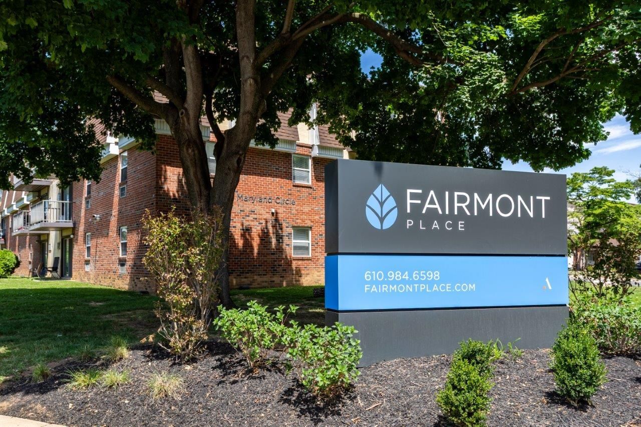 Fairmont Place sign beside a brick building and trees on a sunny day