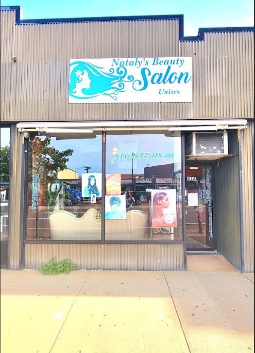 Natalie's Beauty Salon storefront with sign, blue logo, and posters in the window. Exterior shot.