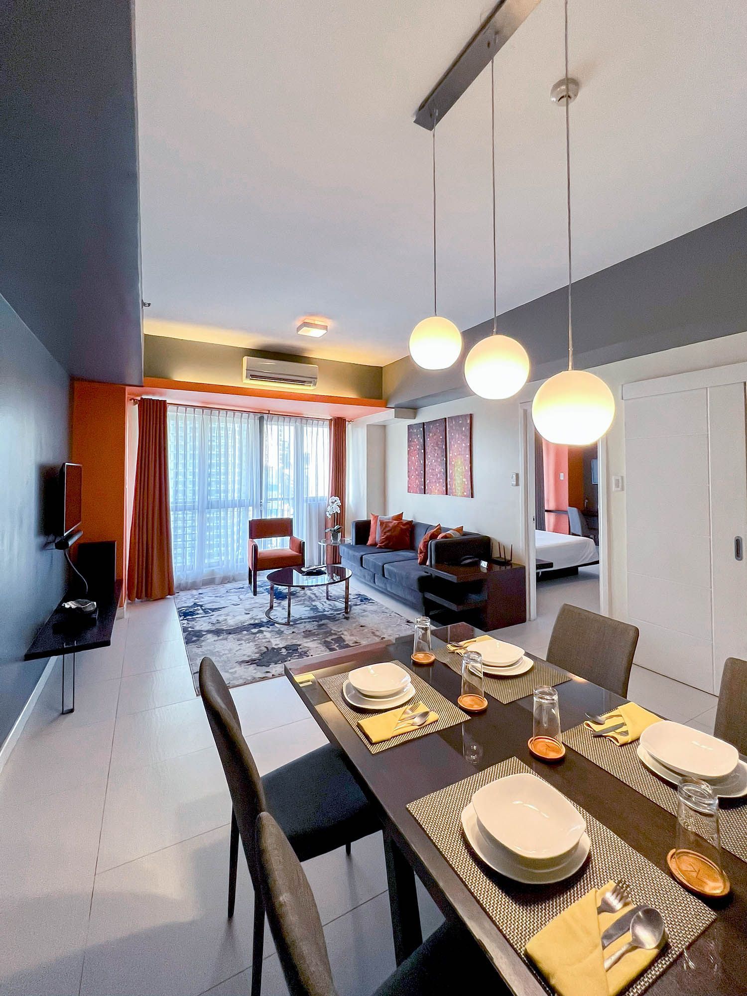 Dining area with a table set for a meal, connected to a living room with a couch and tv.