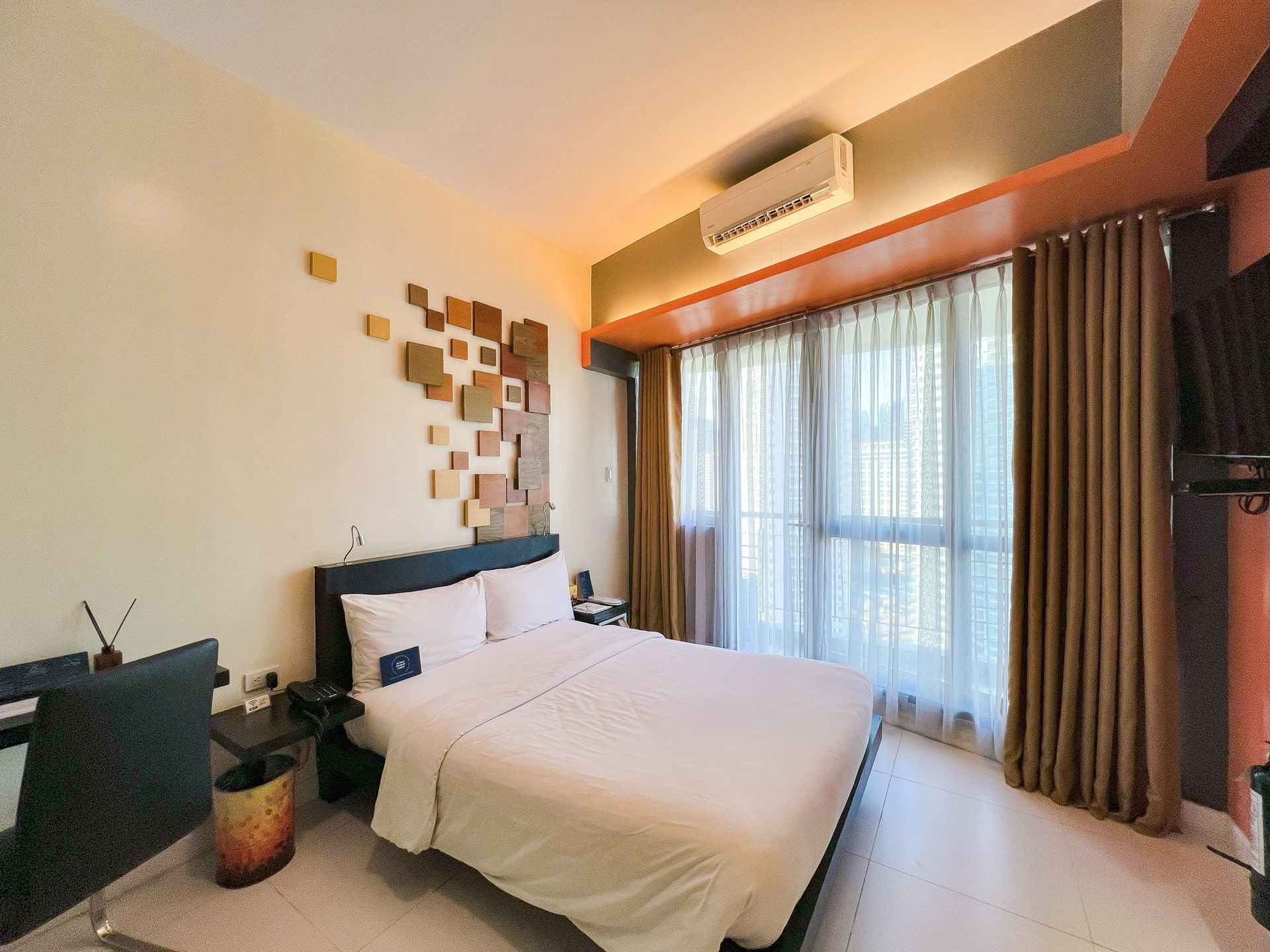 Bedroom with a bed, desk, and large window with curtains. Neutral colors, modern style.