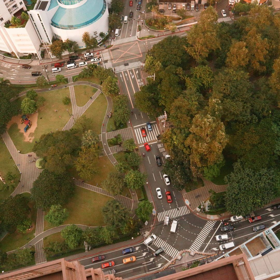 Aerial view of city street with cars, crosswalk, and park with trees.