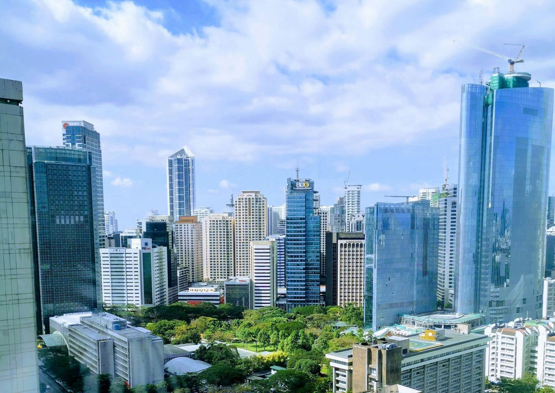 Makati city skyline with  tall buildings and trees in the foreground.